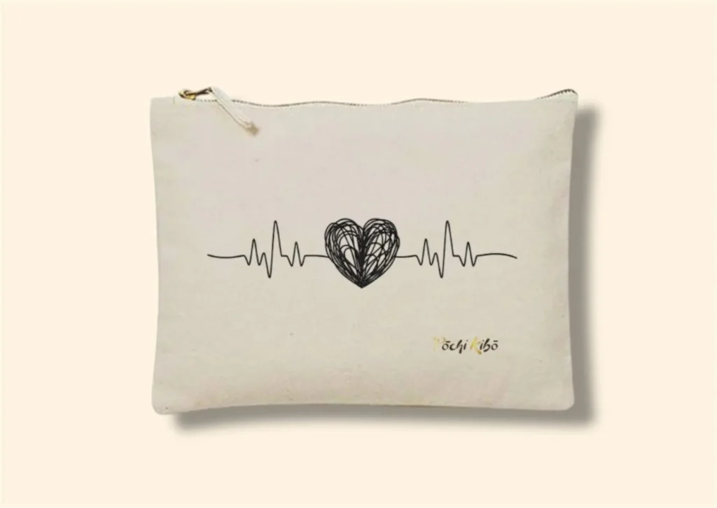 Pochette Pochi Émotions beige photographiée de face sur fond beige, tracé débutant par une ligne de fréquence cardiaque, formant un cœur noir au milieu, et reprenant la fréquence cardiaque à la fin, logo Pochi Kibo en bas à droite. Pochettes d’accompagnement et de soutien.