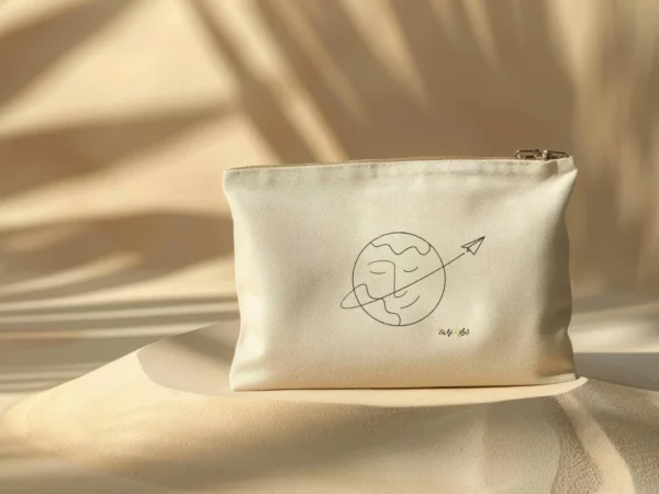 pochette-pochi-voyage Pochette Pochi Voyage avec un tracé représentant une Terre souriante et un tracé continu se terminant par un avion en papier, logo Pochi Kibo en bas à droite, posée sur un dôme de sable avec fond beige assorti et ombres végétales, ambiance naturelle et douce.